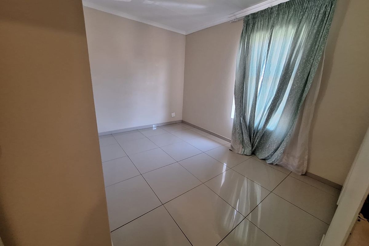 A bright, empty bedroom featuring neutral wall paint, large format floor tiles, and ceiling cornicing, providing a clean canvas for personalization.