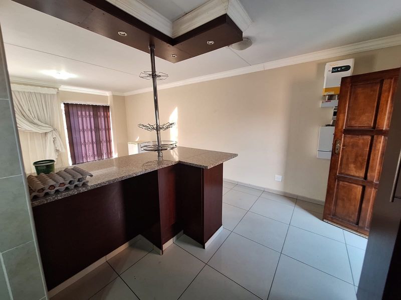 Kitchen area featuring a granite breakfast bar, tiled flooring, and a ceiling bulkhead with recessed lighting.