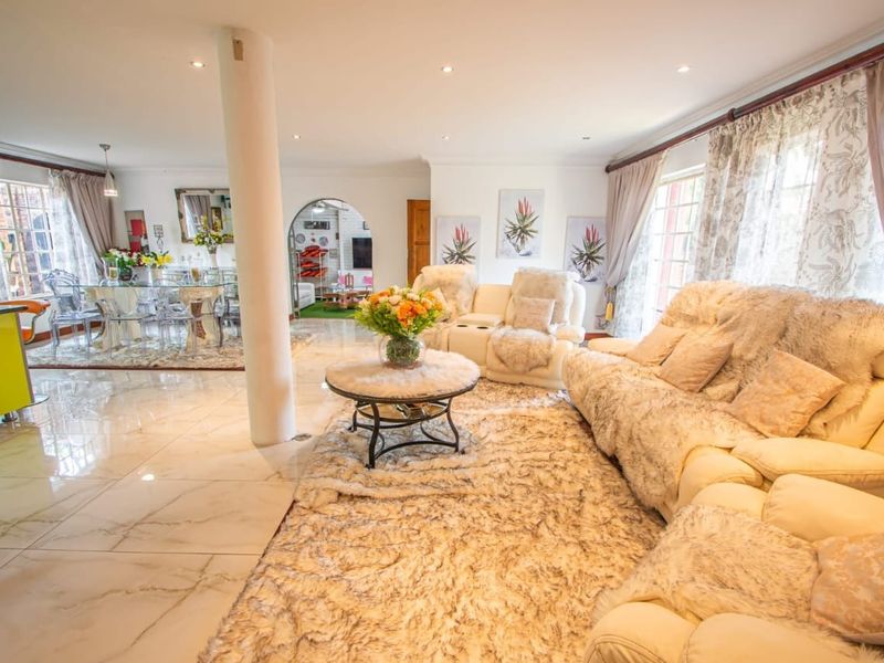 Spacious open-plan living and dining area featuring polished marble-look flooring, recessed lighting, and a central structural column connecting to an adjacent room.