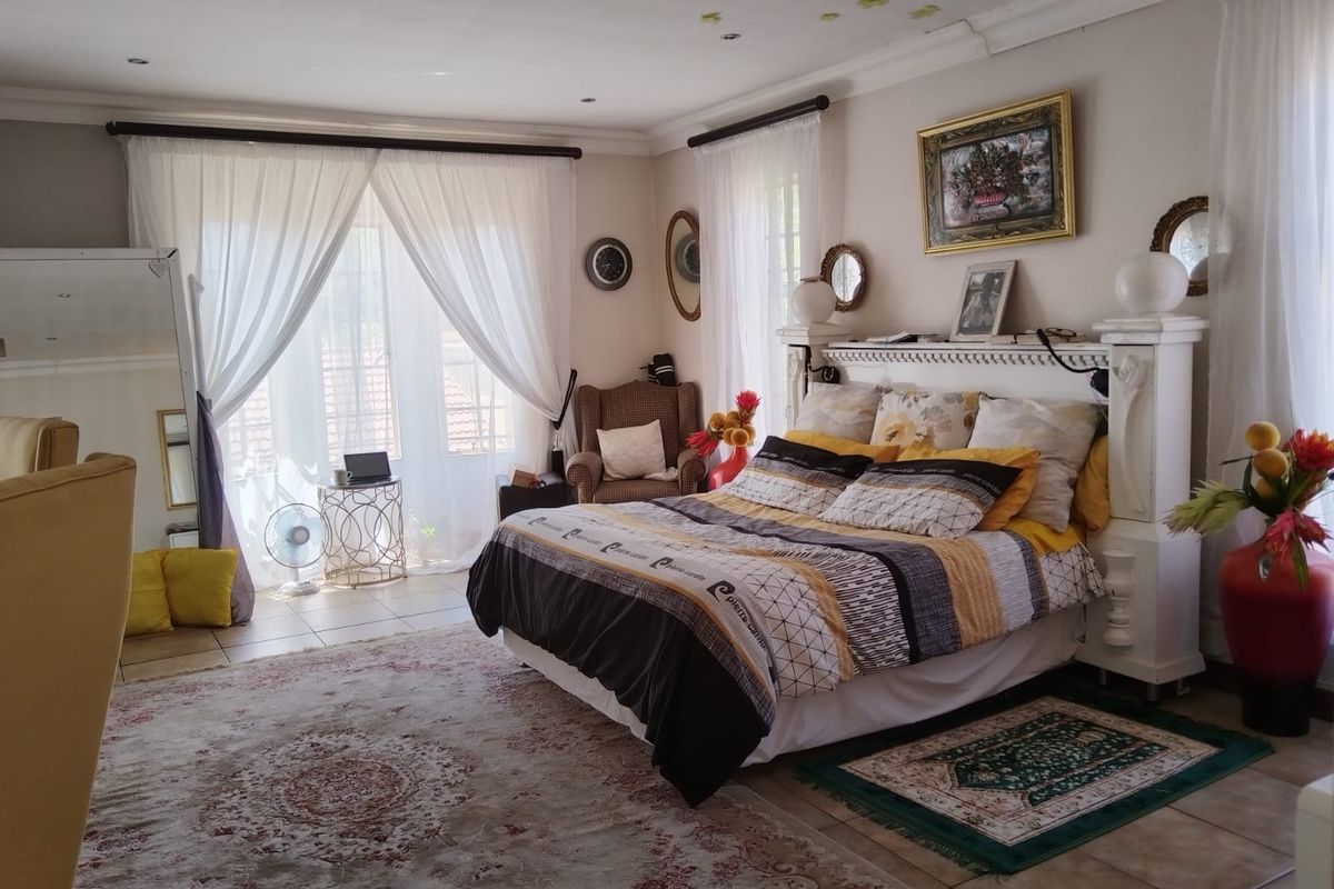 Spacious bedroom featuring tiled flooring, recessed ceiling lighting, and a large sliding glass door providing access to the exterior.