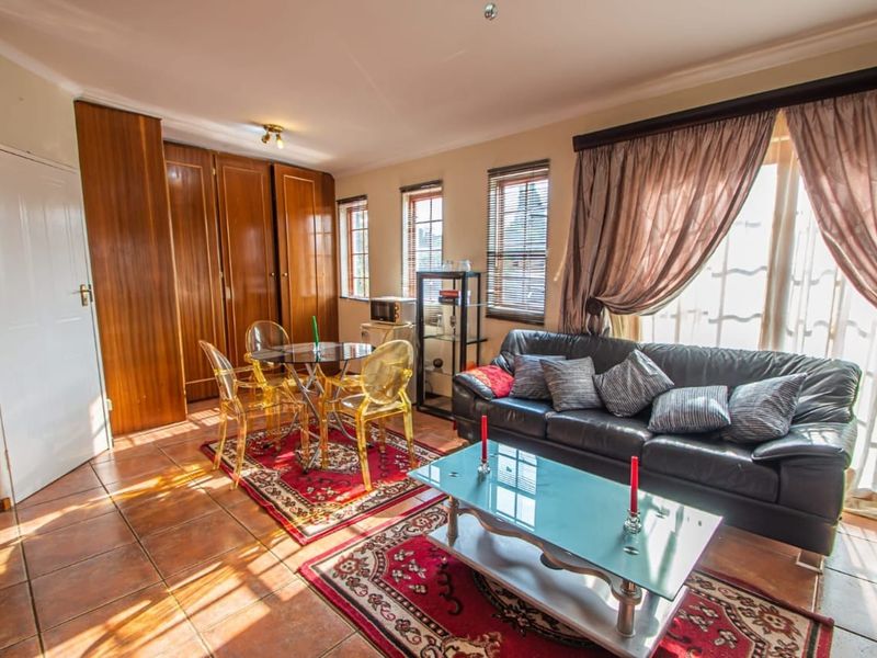 A living room featuring tiled flooring, built-in wooden cabinetry, and access to an outdoor area through a sliding glass door.