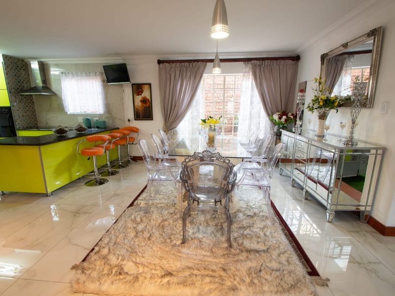 Open-plan living and dining area featuring a modern kitchen with high-gloss cabinetry, granite countertops, and polished tiled flooring throughout.