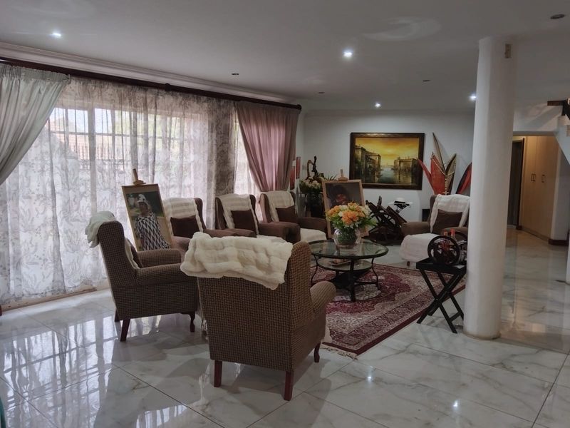 Spacious living room featuring polished marble-look floor tiles, recessed downlighting, and large sliding glass doors that provide ample natural light.
