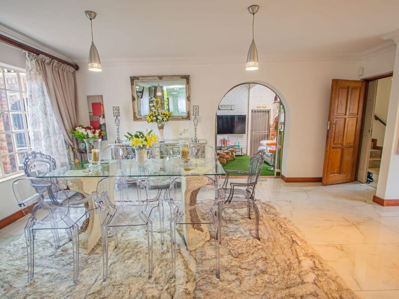 A bright dining room featuring polished marble-look floor tiles, an elegant arched doorway, and modern pendant lighting, creating a welcoming space for meals.