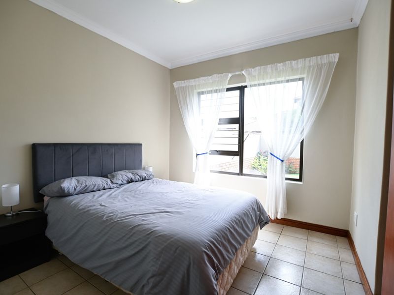 A well-lit bedroom featuring tiled flooring, neutral wall tones, and a built-in cupboard, offering a functional and comfortable living space.