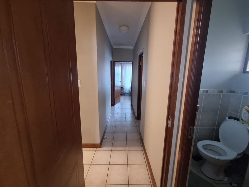 A functional hallway featuring tiled flooring and wooden door frames, providing access to adjacent rooms including a bathroom.