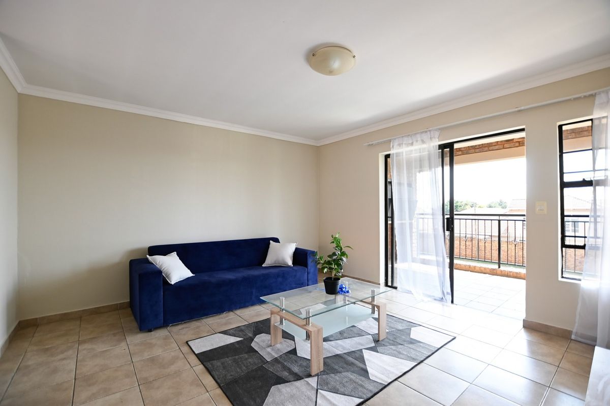 A bright living room featuring tiled flooring and a sliding glass door providing direct access to an outdoor balcony area.