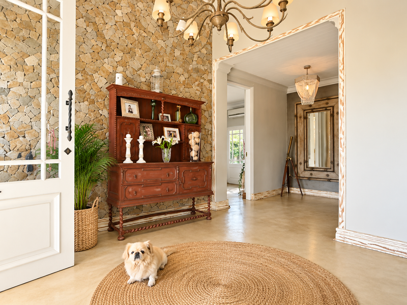 Welcoming entrance hall featuring a striking stone feature wall, polished concrete floors, and elegant chandelier lighting.