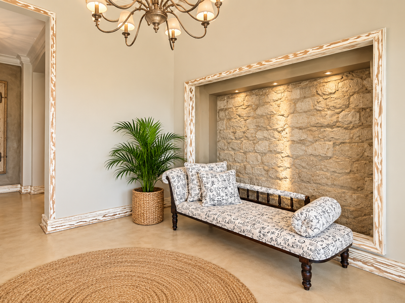 Elegant living area featuring a rustic stone feature wall with recessed lighting, polished concrete floors, and decorative timber architraves.