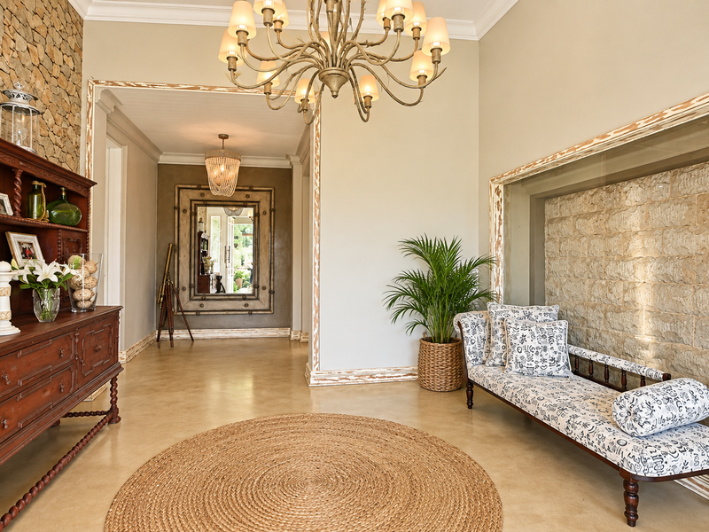 Elegant entrance hall featuring polished concrete floors, a striking stone feature wall, and a decorative chandelier, creating a sophisticated and welcoming atmosphere.