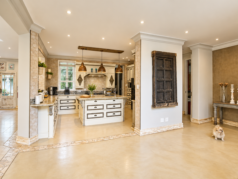 A spacious, well-appointed kitchen featuring a central island, granite countertops, custom cabinetry, and elegant stone accents, seamlessly integrated into an open-plan living area.