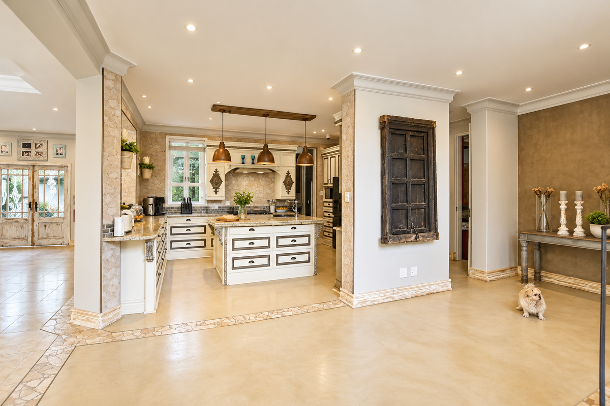 A spacious, well-appointed kitchen featuring a central island, granite countertops, custom cabinetry, and elegant stone accents, seamlessly integrated into an open-plan living area.