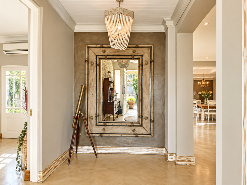 Welcoming entrance hall featuring polished concrete floors, decorative crown molding, and a statement beaded chandelier, providing a bright transition between living spaces.