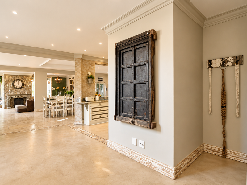 Spacious open-plan living area featuring stone-tiled floors, recessed lighting, crown molding, and a prominent stone-clad fireplace, creating a warm and inviting atmosphere.