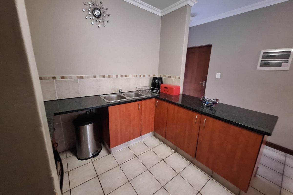 A functional kitchen featuring granite countertops, double bowl sink, tiled backsplash, and laminate cabinetry with neutral wall finishes.