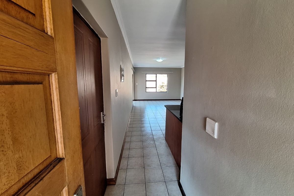 An entrance hallway leading into an open-plan living area with tiled flooring and neutral wall finishes.