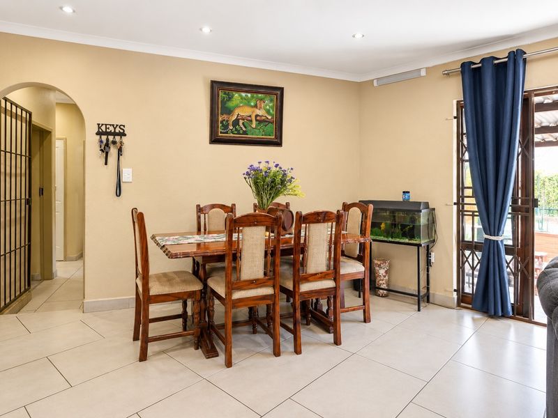 A dining area featuring tiled flooring, recessed downlights, and an arched entryway, with direct access to an outdoor patio through a sliding glass door.