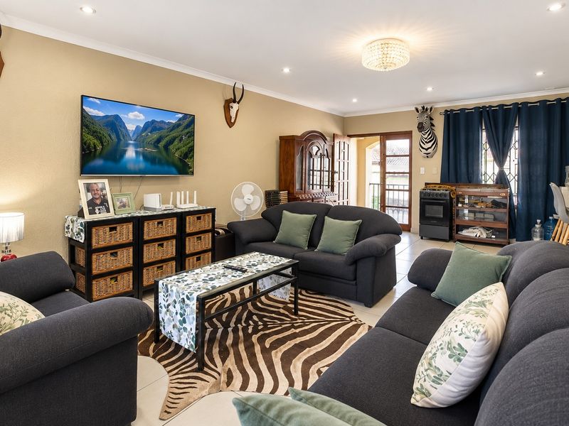 A comfortable living room featuring tiled flooring, recessed downlighting, and direct access to an outdoor area through a glass-paneled door.