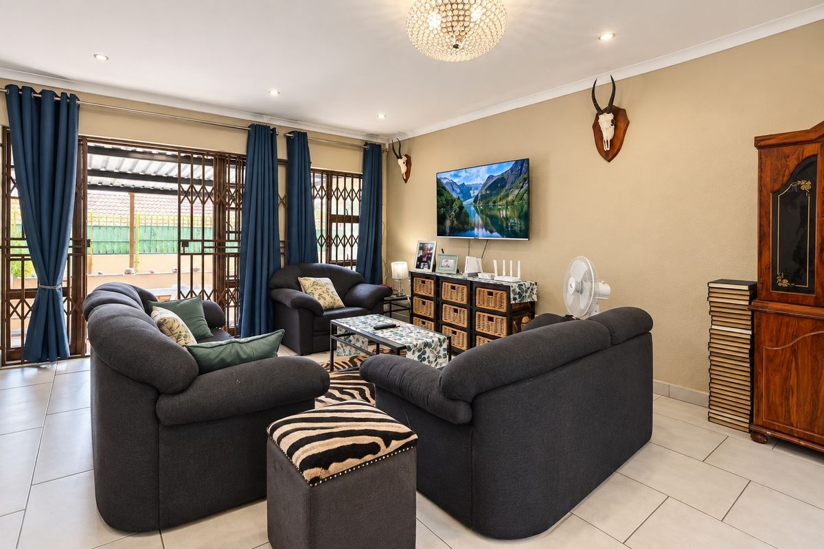 A comfortable living room featuring tiled flooring, recessed lighting, and sliding glass doors that provide access to the outdoor area.
