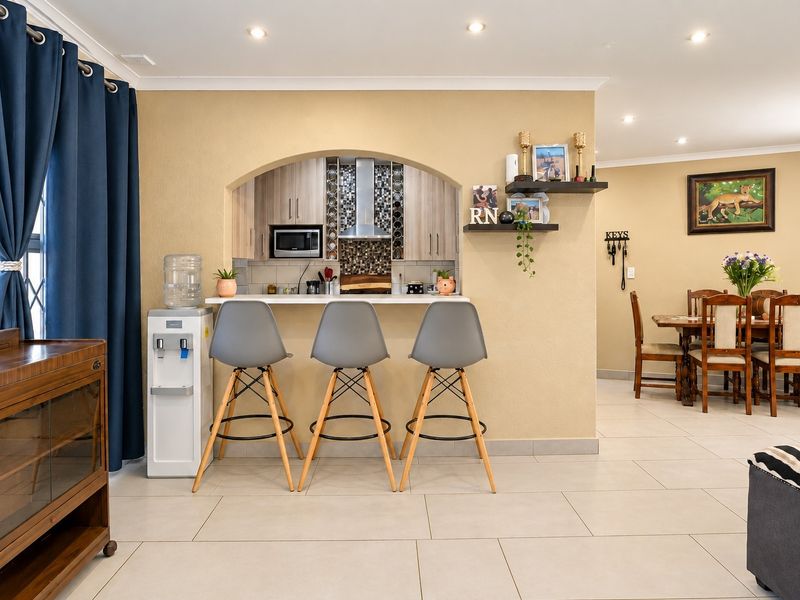 Open plan living area featuring a kitchen nook with built-in cabinetry, stainless steel extractor, and tiled flooring throughout.
