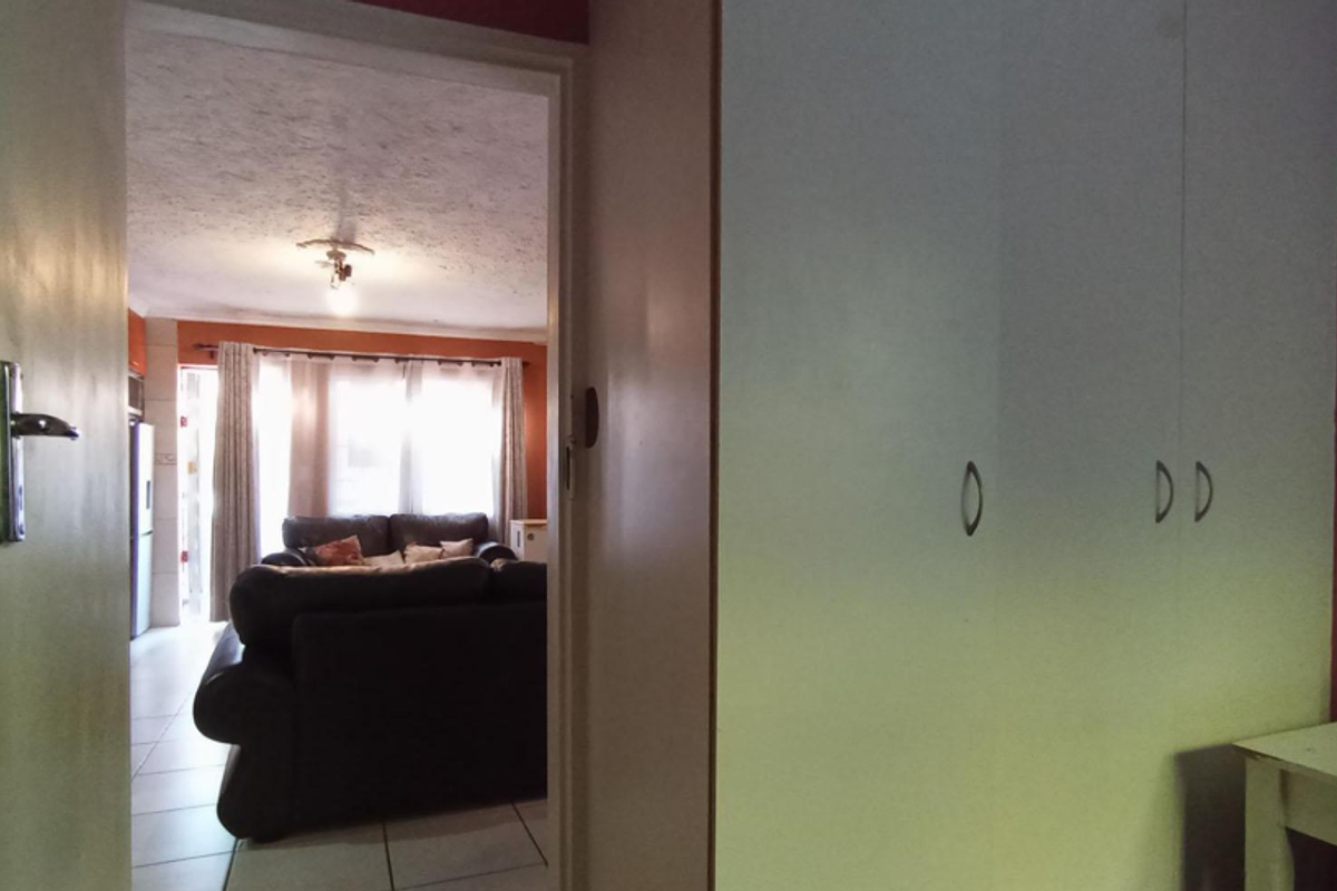 A bedroom featuring built-in cupboards, with a doorway providing a view into the adjacent living area.