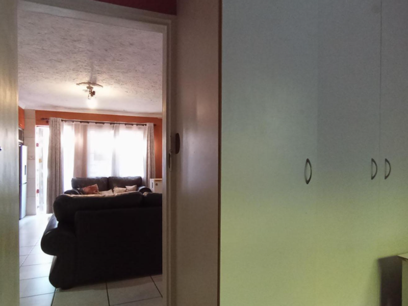 A bedroom featuring built-in cupboards, with a doorway providing a view into the adjacent living area.