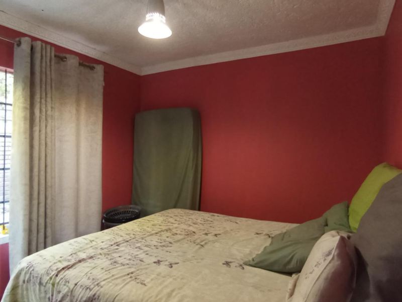 A bedroom featuring red walls, a ceiling cornice, and a sliding glass door with an external security gate providing access to the exterior.