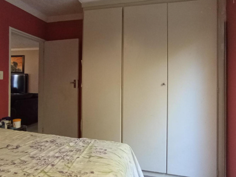 A bedroom featuring built-in wardrobes, red painted walls, and direct access to an outdoor area through a security gate.