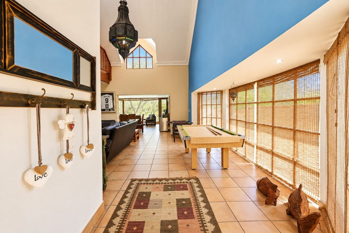 Spacious living area featuring high vaulted ceilings, tiled flooring, and large windows that provide ample natural light and a view of the outdoors.