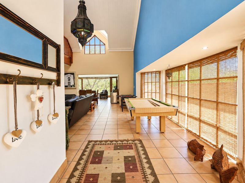 Spacious living area featuring high vaulted ceilings, tiled flooring, and large windows that provide ample natural light and a view of the outdoors.