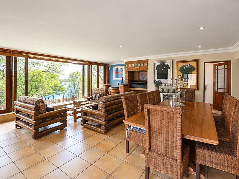 Spacious open-plan living and dining area featuring tiled floors, a built-in brick fireplace, and expansive sliding doors offering scenic outdoor views.