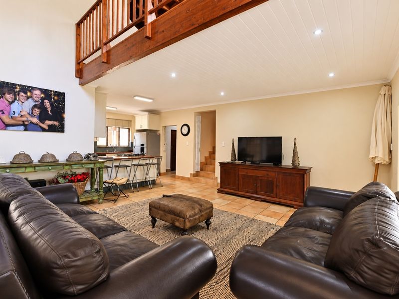 Spacious open-plan living area featuring tiled floors, a timber mezzanine level, and an integrated kitchen with a breakfast bar.