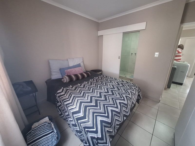 A bedroom featuring tiled flooring and a sliding door providing access to an en-suite bathroom.