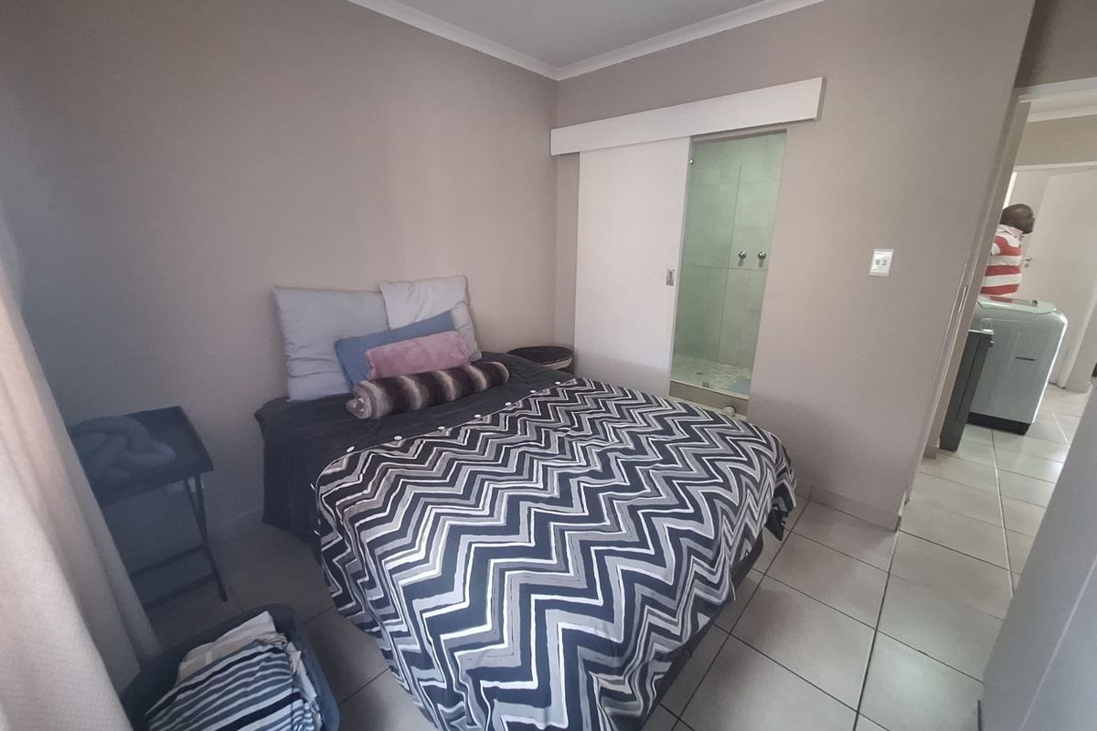 A bedroom featuring tiled flooring and a sliding door providing access to an en-suite bathroom.
