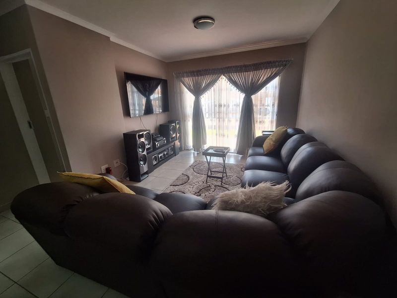 A comfortable living room featuring tiled flooring and a large sliding glass door that provides natural light.