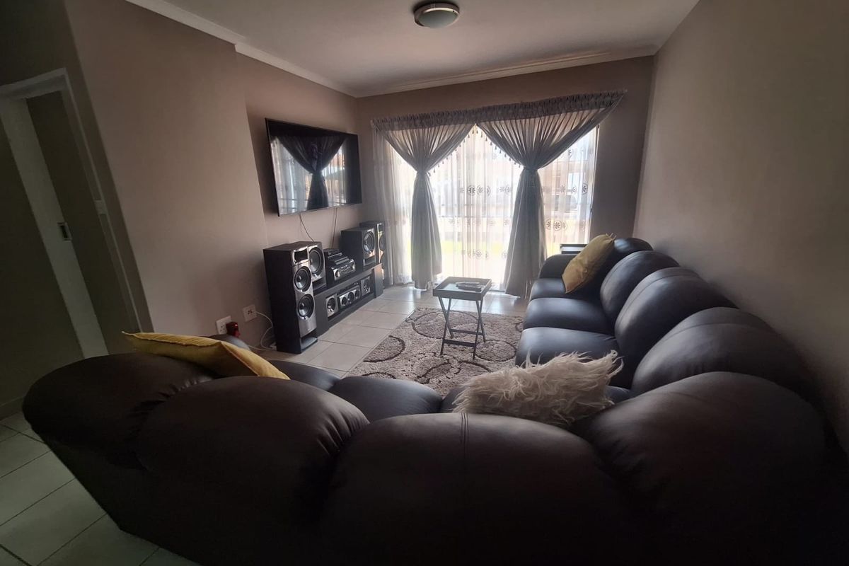 A comfortable living room featuring tiled flooring and a large sliding glass door that provides natural light.