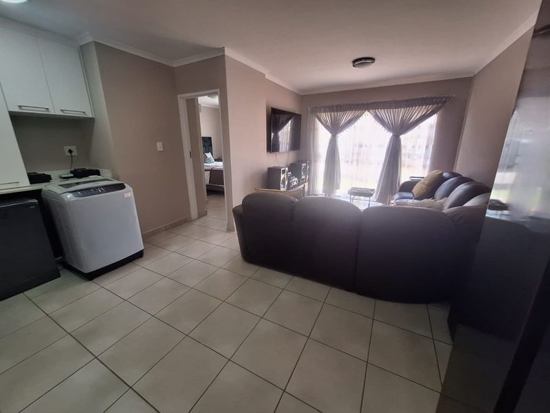 Open-plan living area featuring tiled flooring, built-in kitchen cabinetry, and a sliding glass door leading to the exterior.
