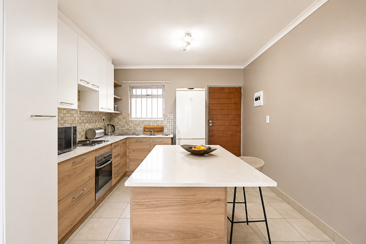 Modern kitchen featuring wood-finish cabinetry, stone countertops, a central island, built-in oven, and tiled flooring, offering a clean and functional workspace.