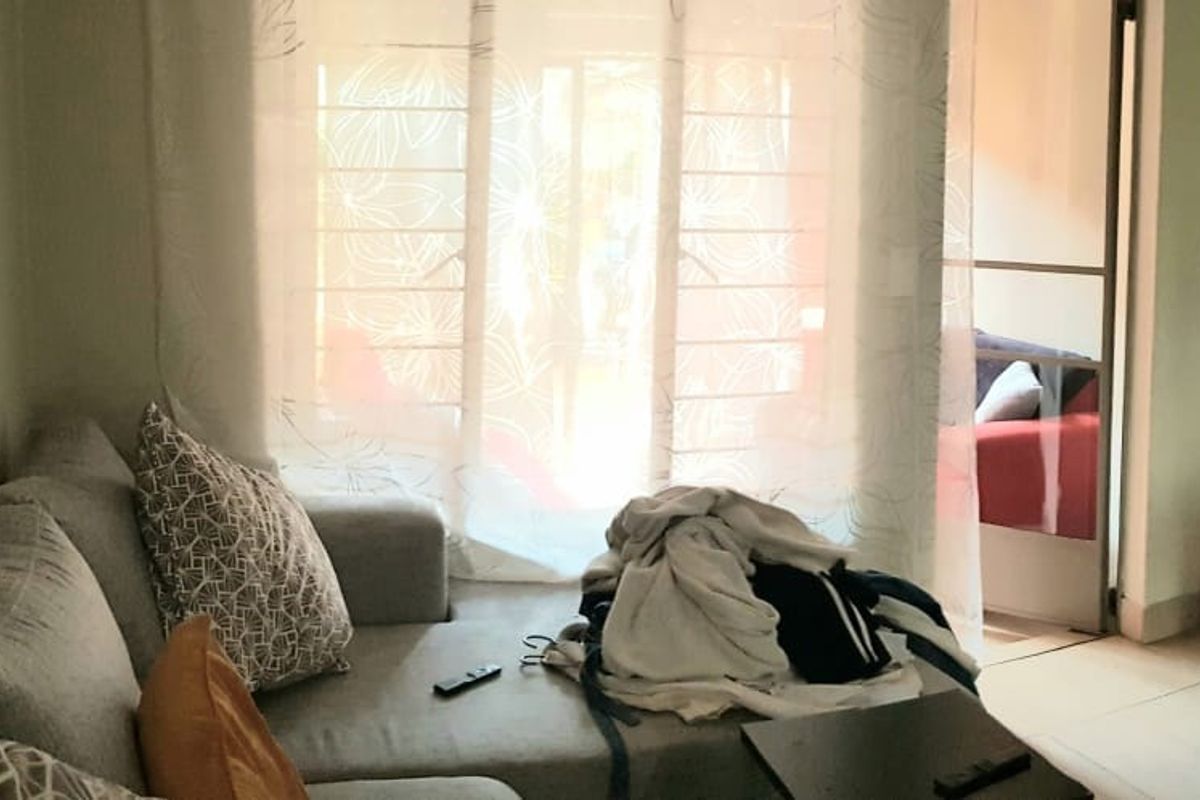 A living room area featuring tiled flooring and a sliding glass door leading to an adjacent space.