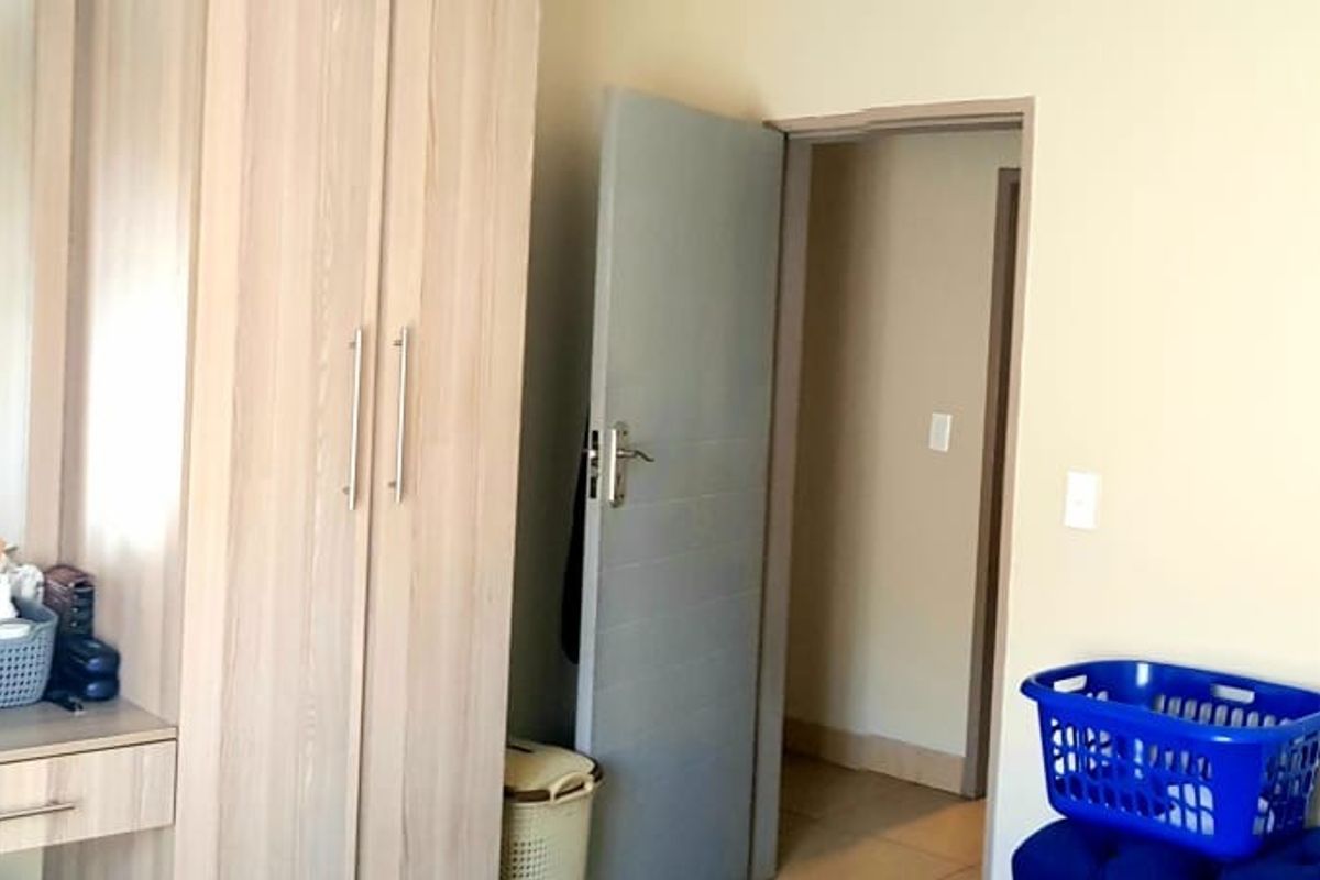A bedroom featuring light wood-toned built-in wardrobes with an integrated vanity and mirror, providing ample storage and functional dressing space.