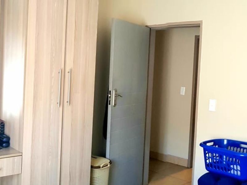 A bedroom featuring light wood-toned built-in wardrobes with an integrated vanity and mirror, providing ample storage and functional dressing space.