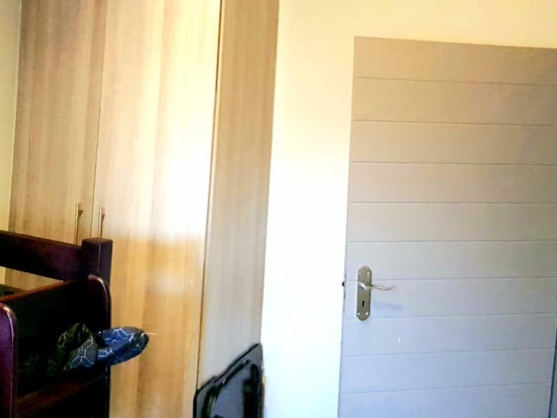 A bedroom featuring a built-in wooden wardrobe and a modern horizontal-panel interior door.