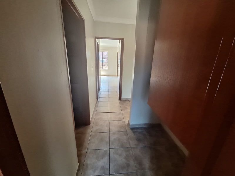 A functional hallway featuring tiled flooring and built-in cabinetry, providing access to other rooms within the townhouse.