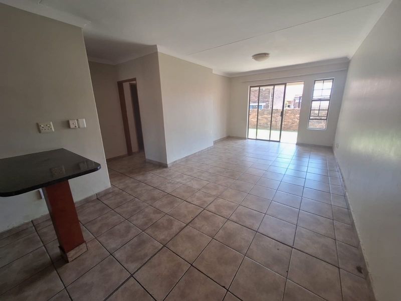 Spacious open-plan living area featuring tiled flooring, a breakfast counter, and a sliding glass door providing access to the exterior.