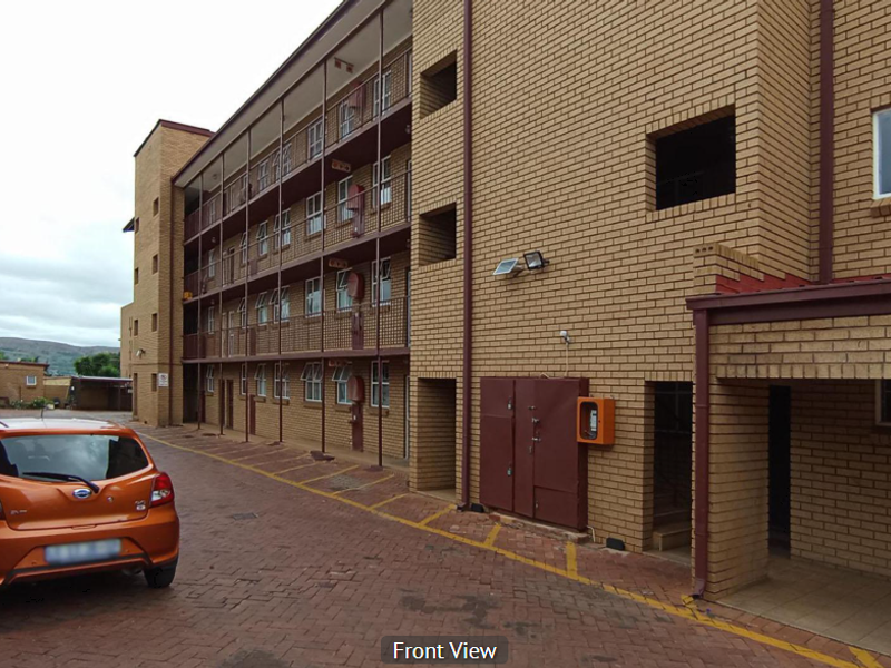 Exterior view of a multi-story apartment complex featuring face brick construction and a paved driveway area.