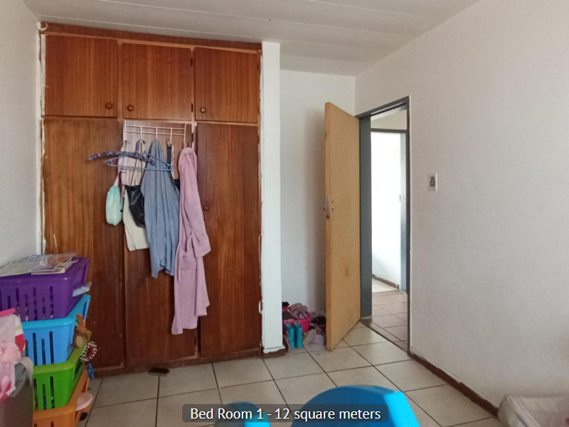 A bedroom featuring built-in wooden cupboards and tiled flooring, offering a functional space ready for updates.