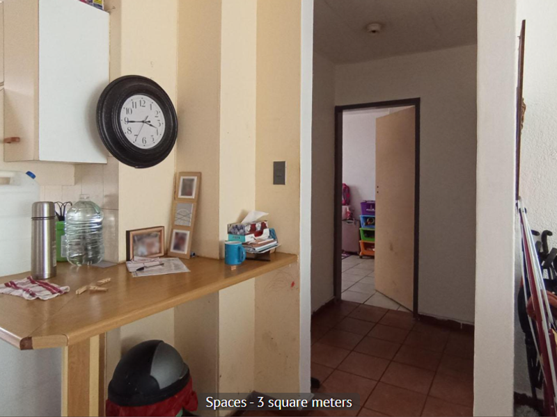 A compact kitchen area featuring a built-in breakfast bar and tiled flooring, leading through to an adjacent room.