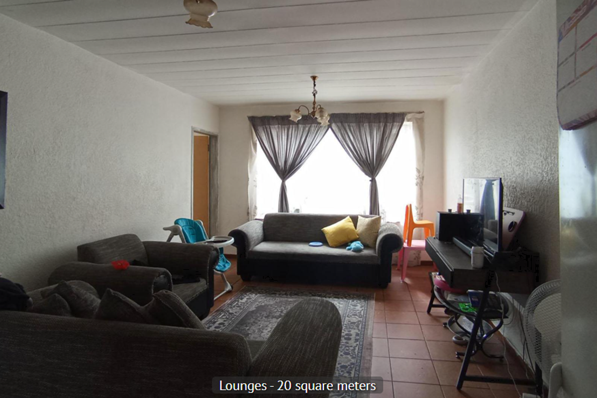 A spacious living room featuring tiled flooring, textured walls, and a panelled ceiling, offering a functional layout for comfortable family living.