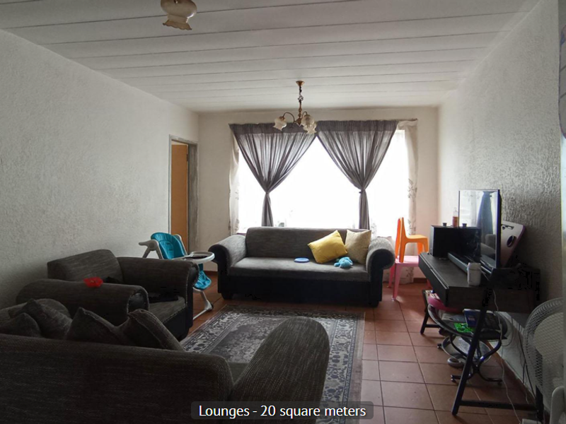 A spacious living room featuring tiled flooring, textured walls, and a panelled ceiling, offering a functional layout for comfortable family living.