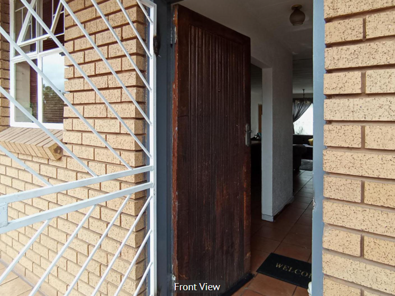 Entrance area featuring a brick facade, security gate, and timber door leading into the interior tiled hallway.